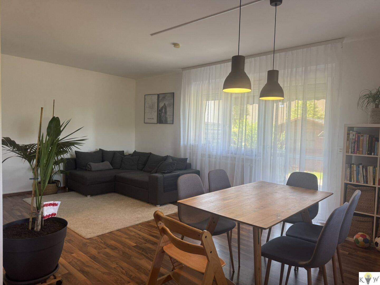 Heller Wohn- und Essbereich mit Esstisch, Sofa und großem Fenster, lichtdurchflutet.