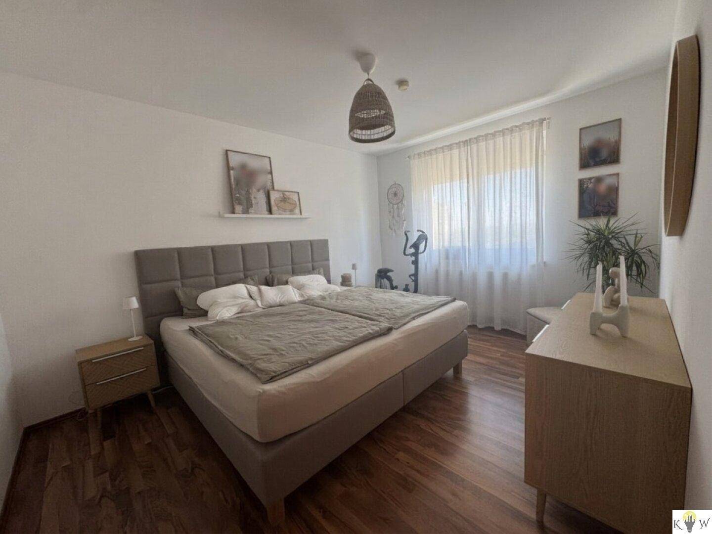 Gemütliches Schlafzimmer mit Doppelbett, Holzboden und Fenster mit Vorhängen.