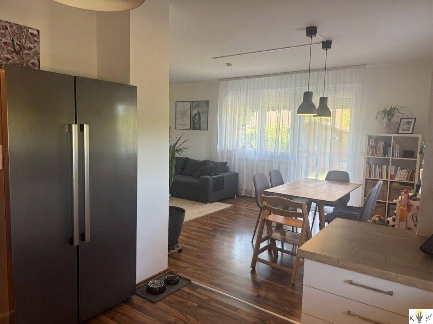 Offener Wohn- und Essbereich mit Blick auf die Küche, ausgestattet mit Holzboden.