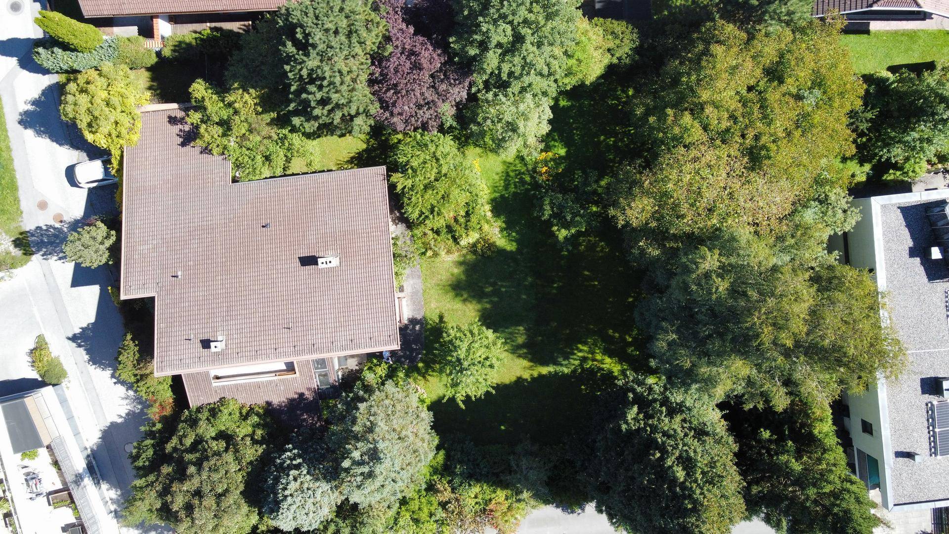 Vogelperspektive des Hauses mit weitläufigem Garten und dichtem Baumbestand in sonniger Lage.
