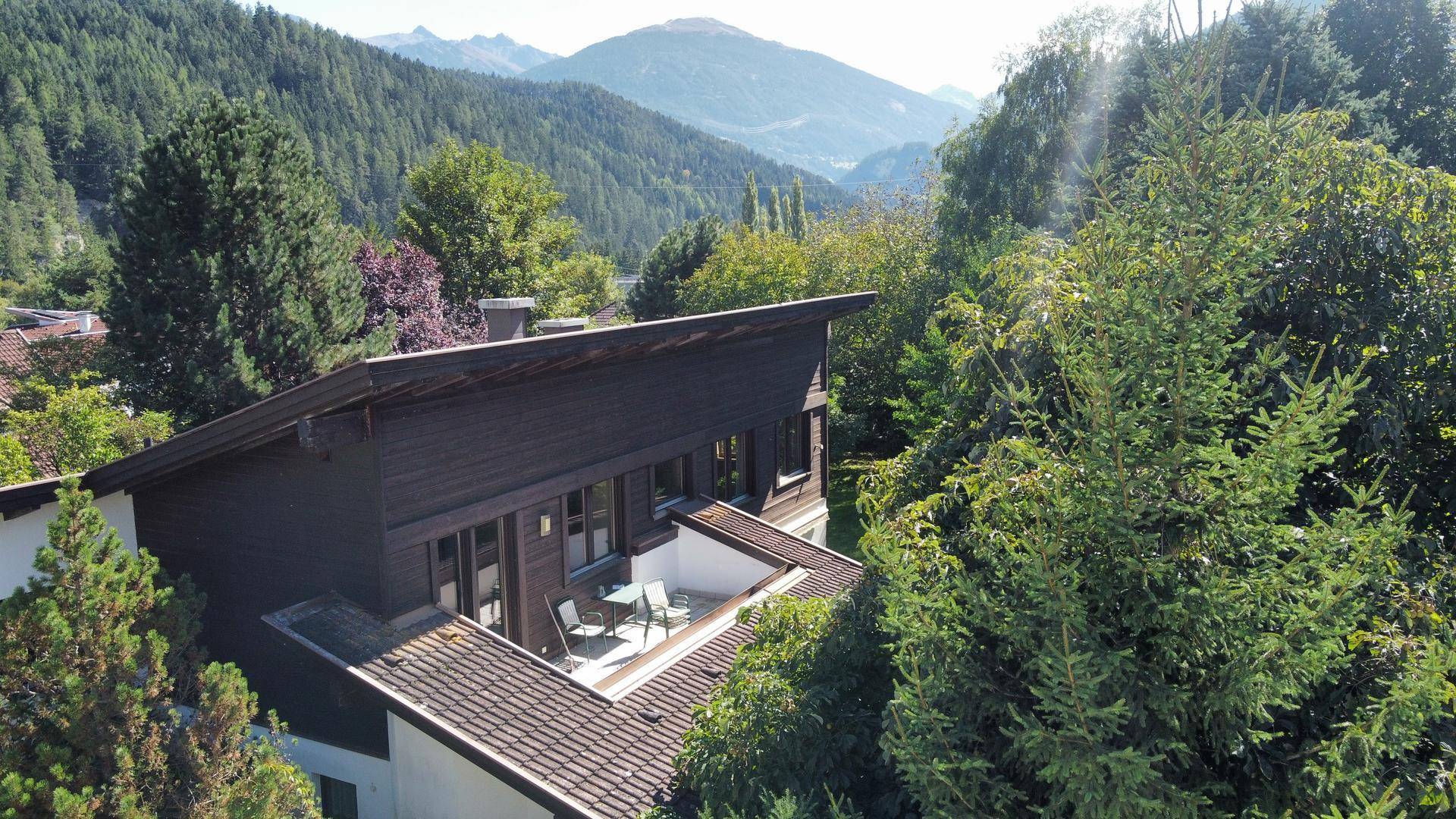Dachterrasse mit Sitzgelegenheiten und weitem Blick auf die bewaldeten Berge und das Tal.