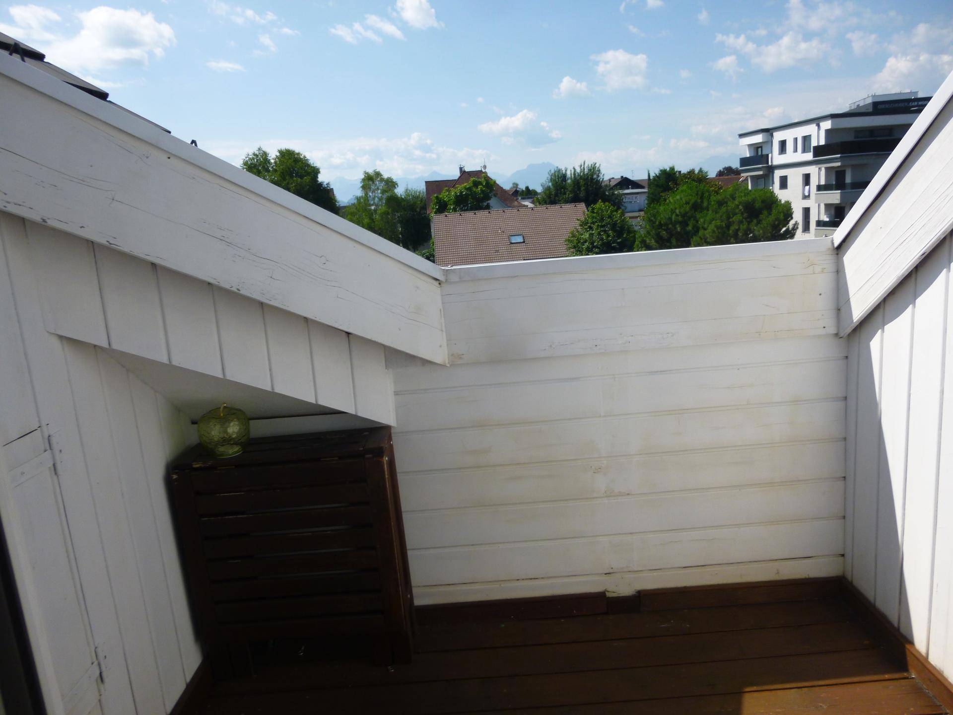 Kleiner Balkon mit Holzverkleidung und Holzboden, bietet Platz für Entspannung im Freien.