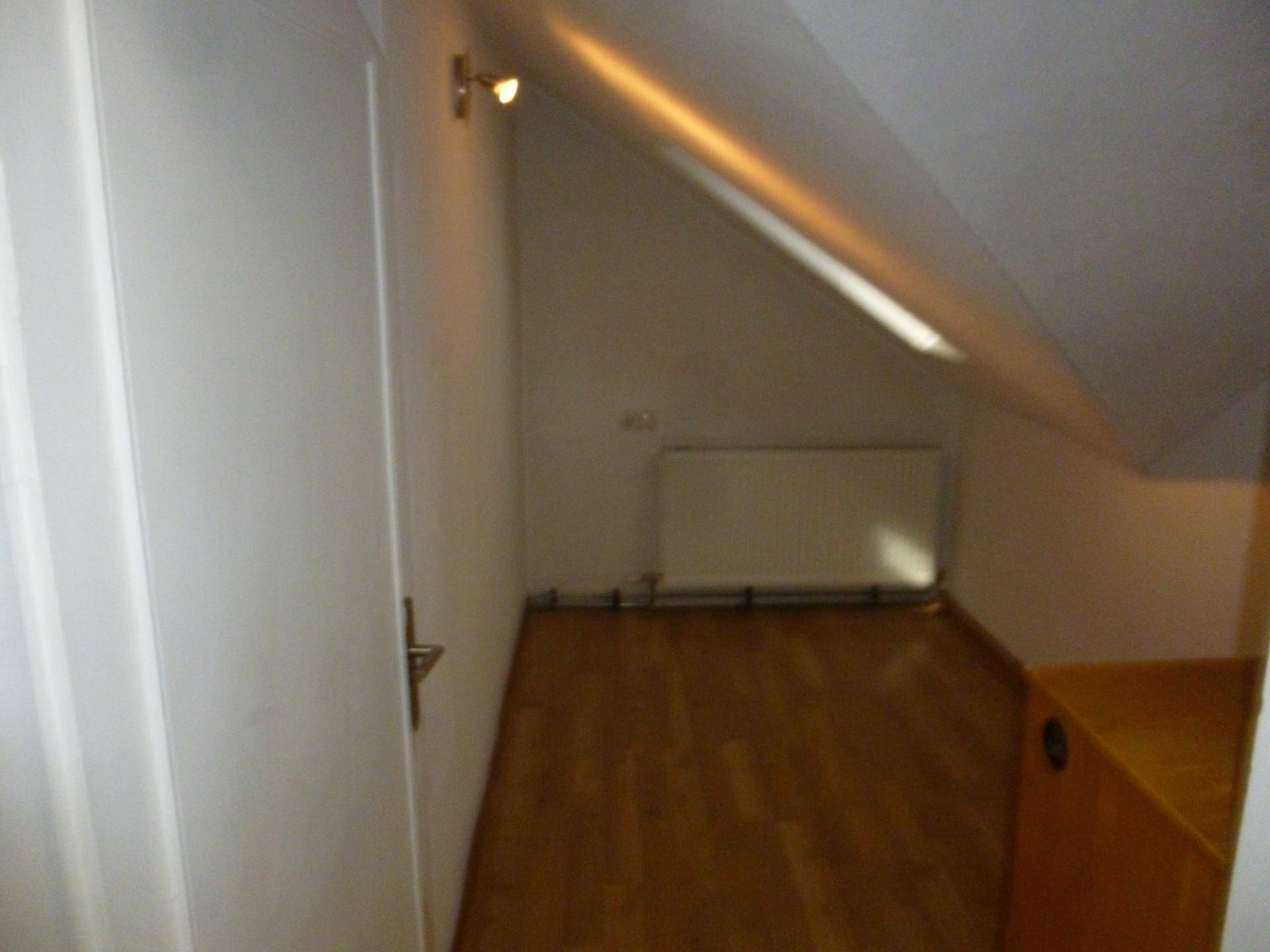 Kleiner Raum im Dachgeschoss mit schräger Decke, Laminatboden und Heizkörper.