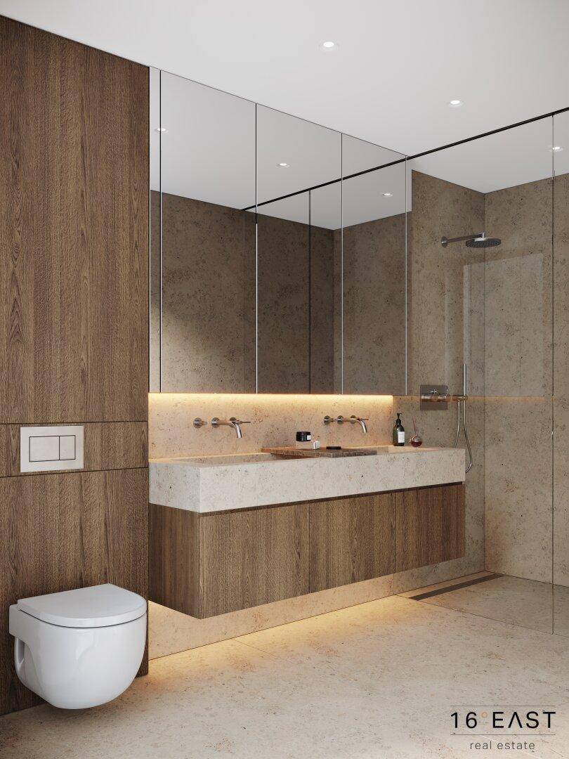 Elegantes Badezimmer mit wandhängendem WC, Doppelwaschbecken und ebenerdiger Dusche.