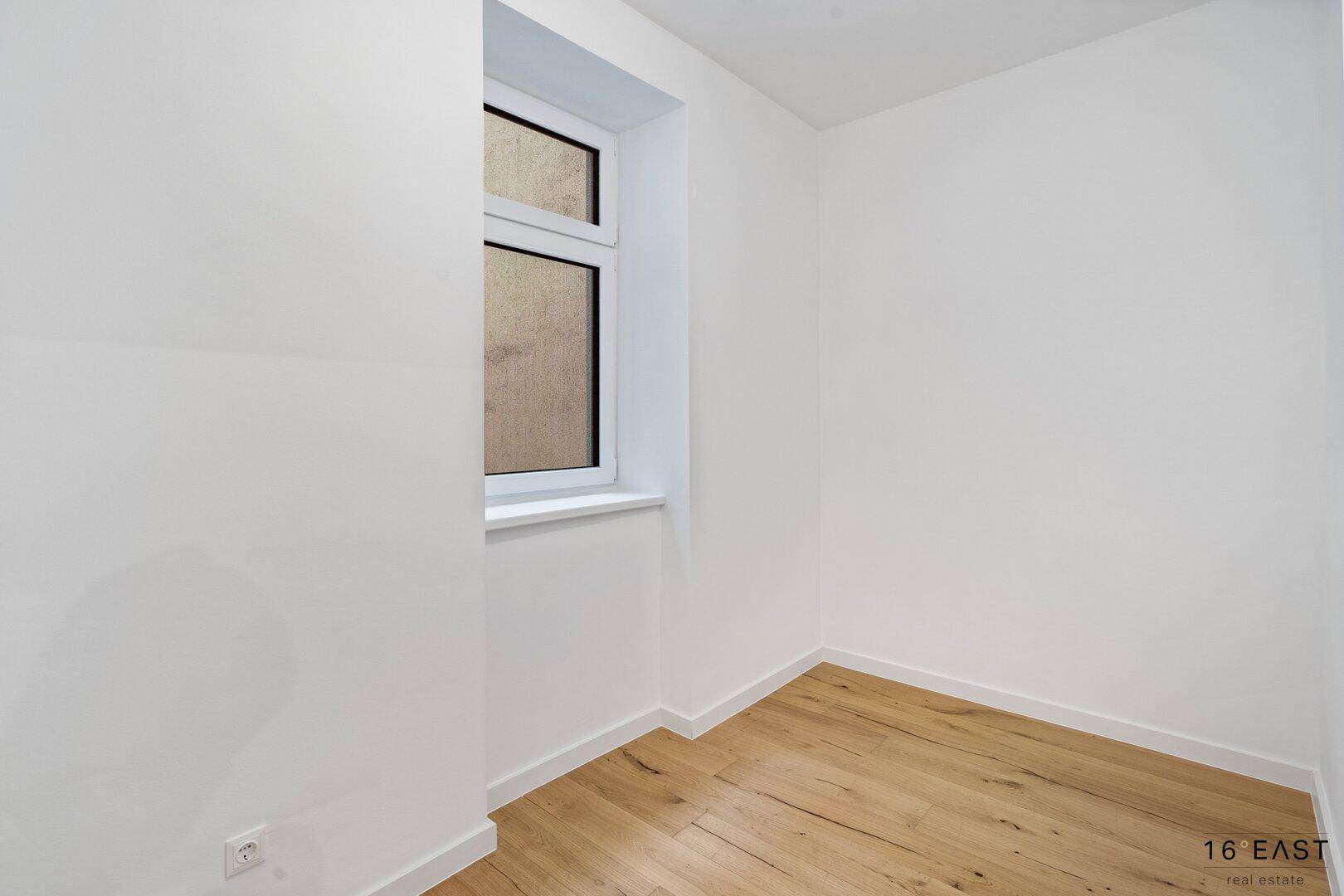 Kleiner, heller Raum mit Holzboden und Fenster, geeignet als Abstellraum oder Ankleidezimmer.
