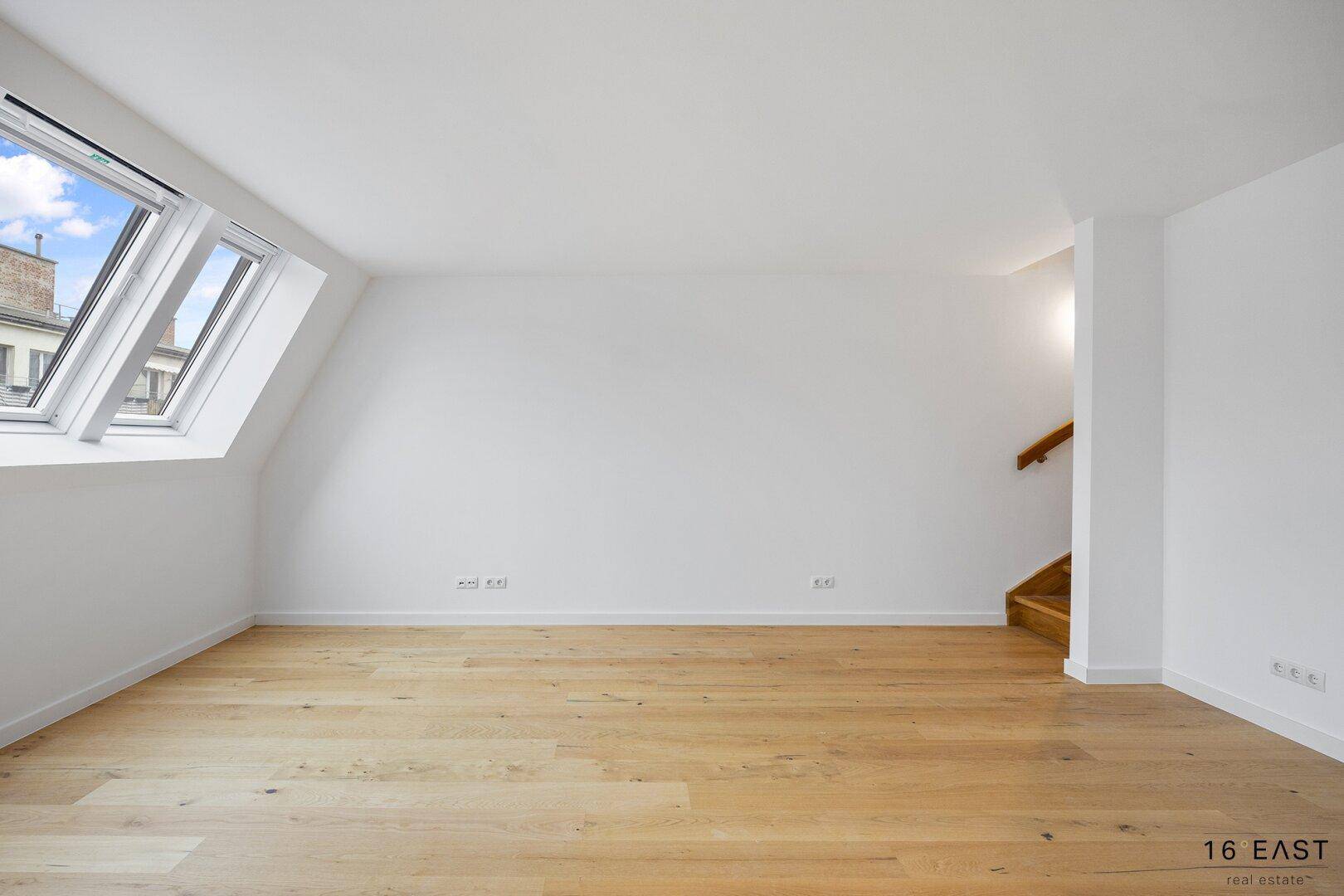 Geräumiger Wohnbereich mit Holzboden, Dachschrägen und hellen Dachfenstern, bietet viel Gestaltungspotenzial.