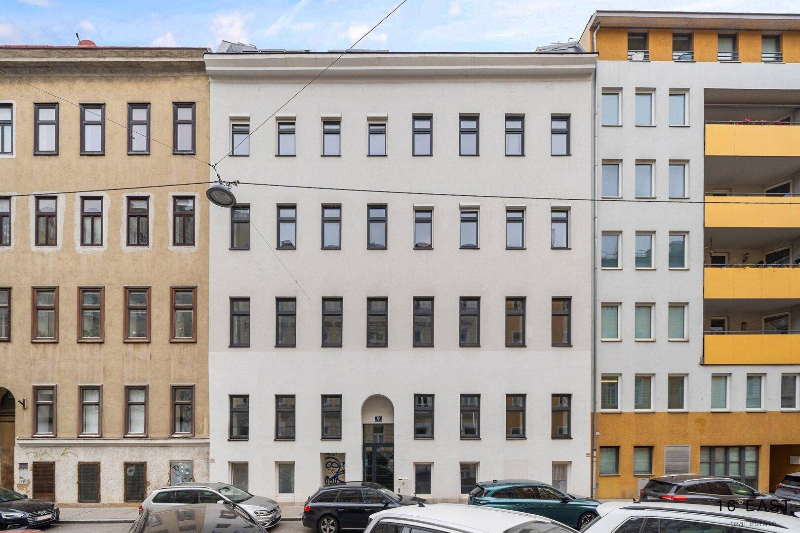 Klassische Fassade eines Mehrfamilienhauses in einer städtischen Umgebung.