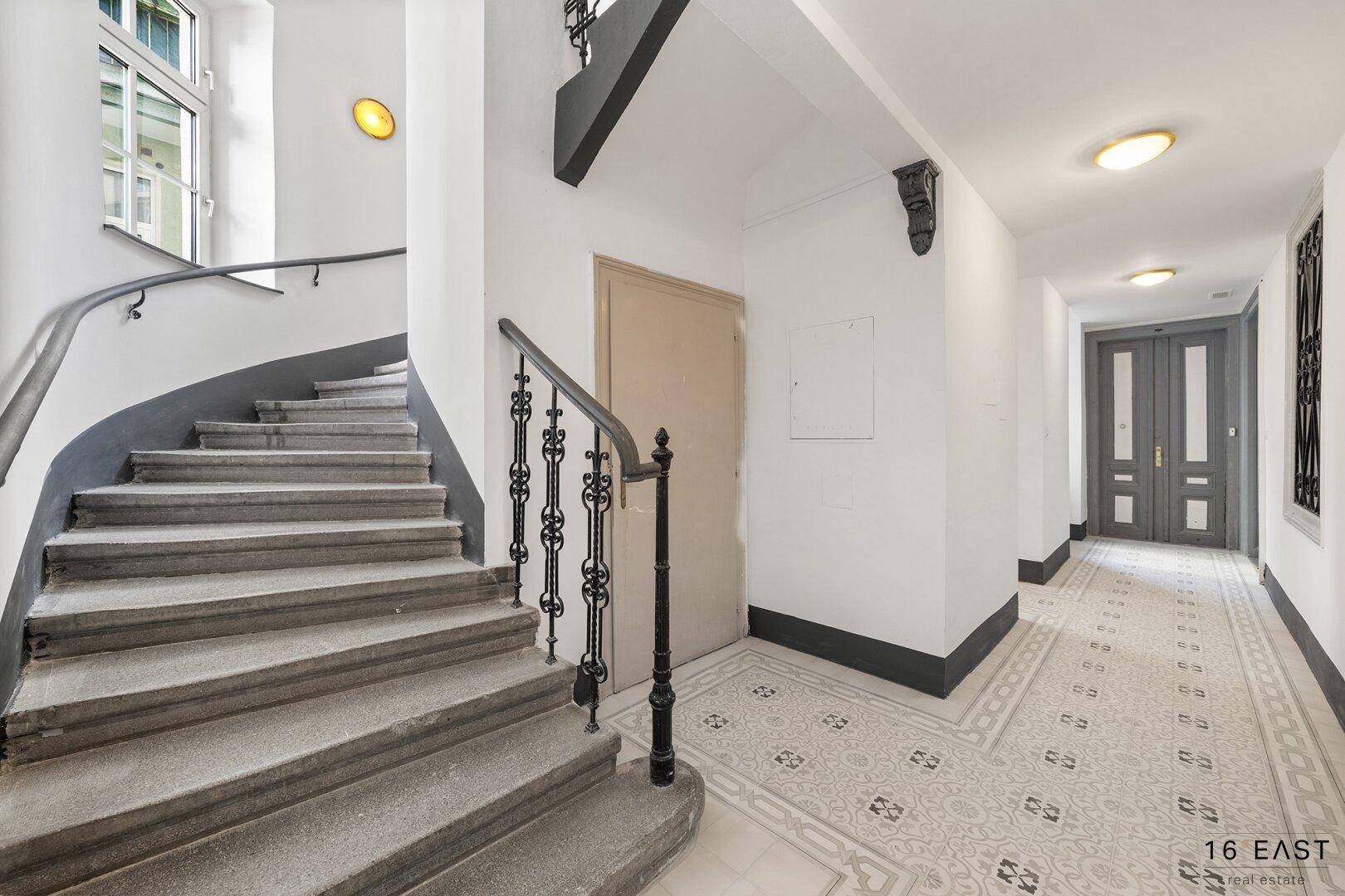Elegantes Treppenhaus mit Steinstufen und kunstvollem Geländer, führt zu den oberen Etagen.