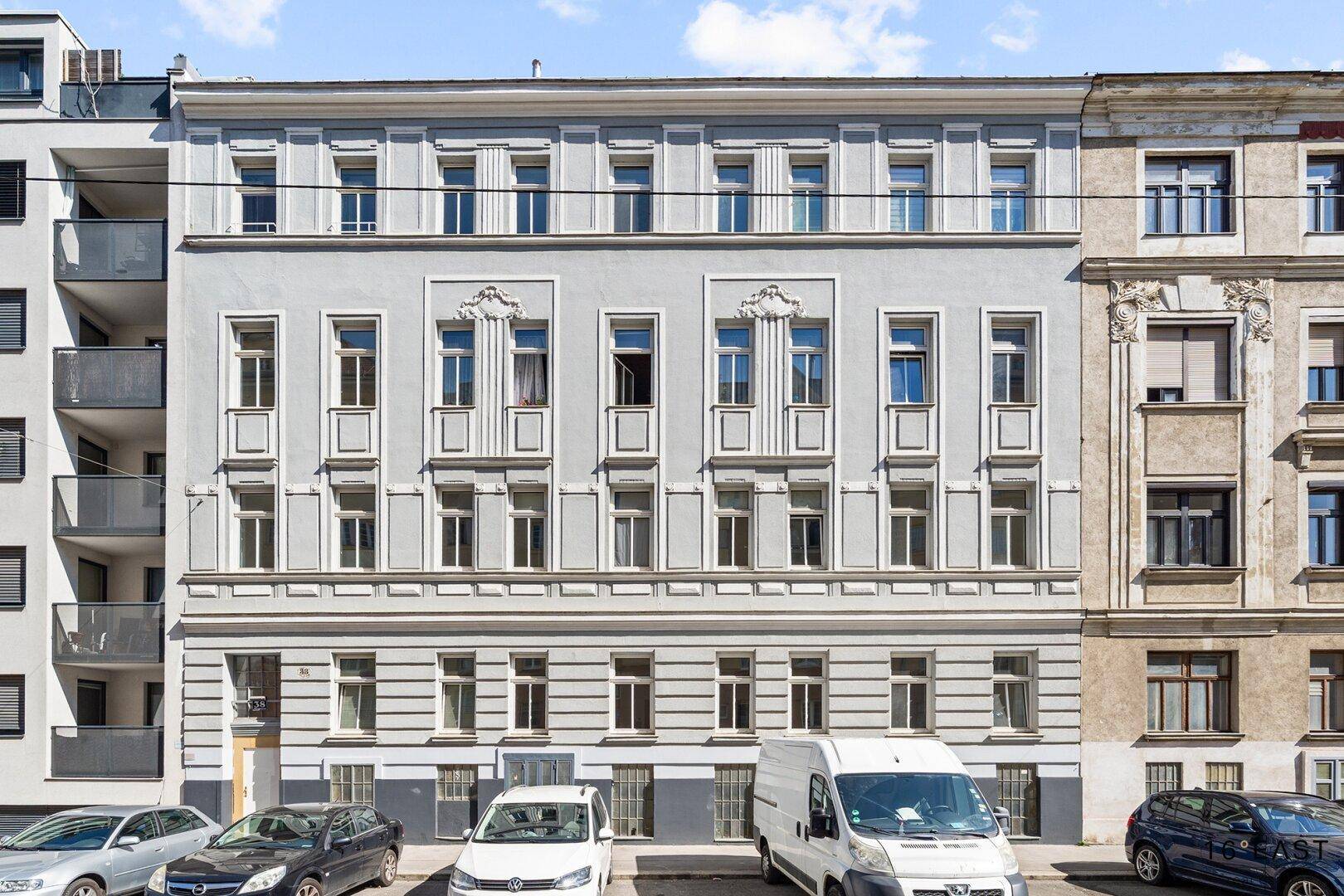 Klassische Fassade eines Mehrfamilienhauses mit vielen Fenstern und historischem Charme.