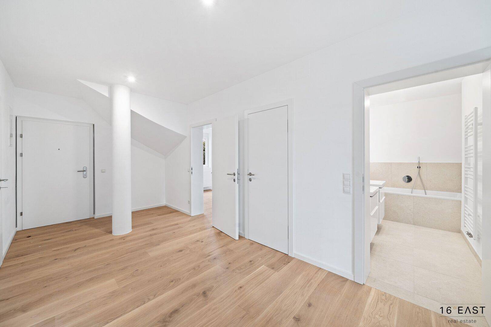 Heller Flur mit Holzboden und Zugang zu einem Badezimmer und weiteren Räumen.