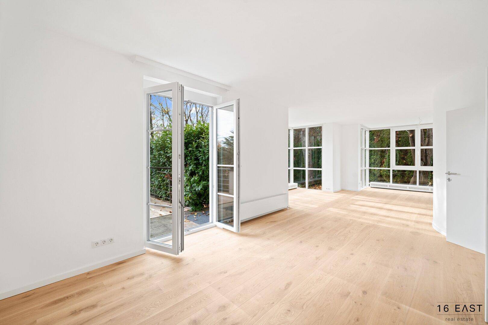 Heller Wohnbereich mit Holzboden und französischen Türen, die auf einen Balkon führen.
