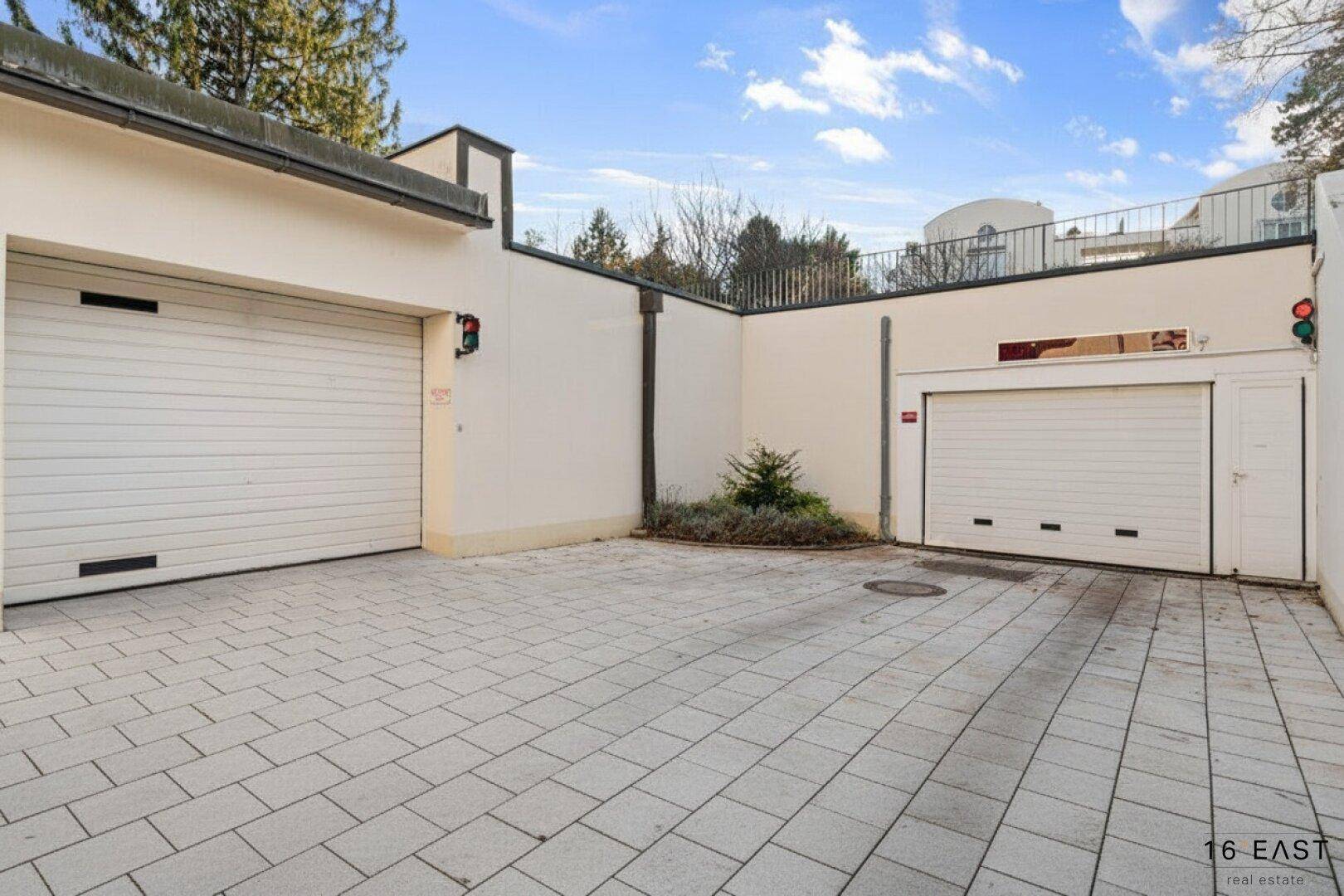 Garagenzufahrt mit zwei Garagentoren und gepflastertem Vorplatz.