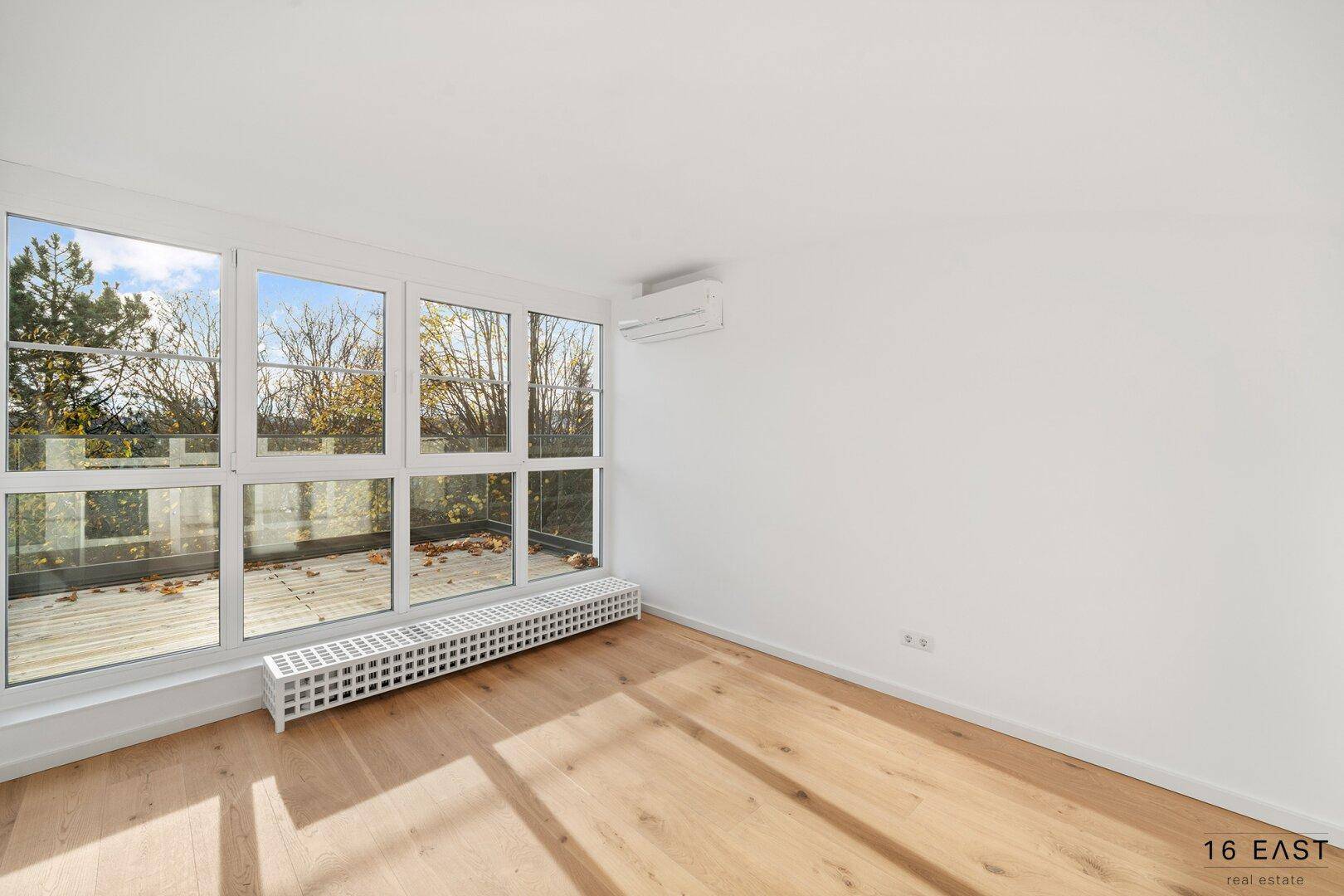 Geräumiges Schlafzimmer mit Holzboden, großen Fenstern und Klimaanlage, bietet einen weiten Blick.
