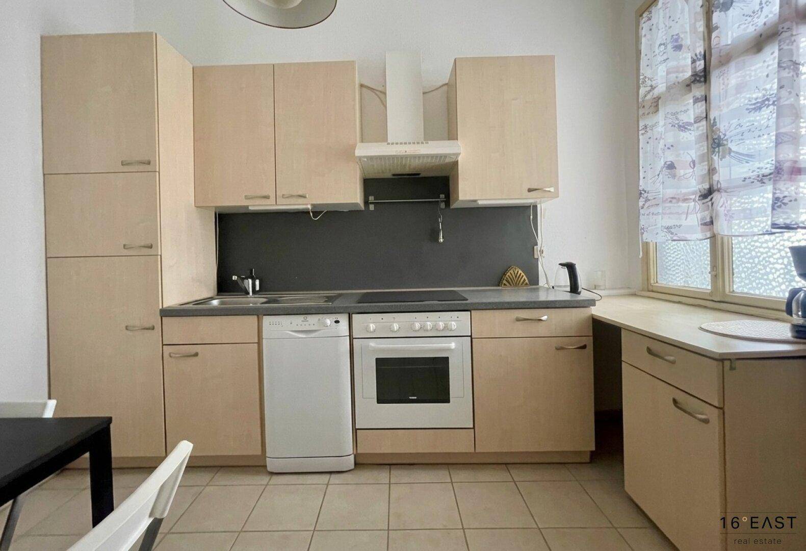 Funktionale Küche mit hellen Holzschränken, integrierten Geräten und Fenster.