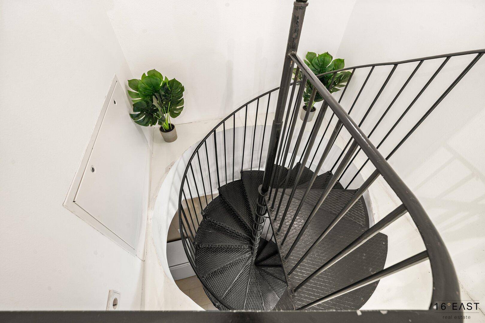 Elegante schwarze Wendeltreppe in einem hellen Treppenhaus.