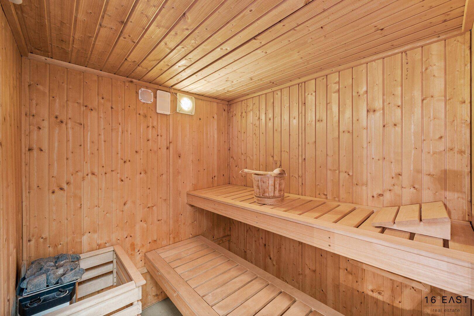 Traditionelle Holzsauna mit Bänken und Saunaofen für Entspannung.