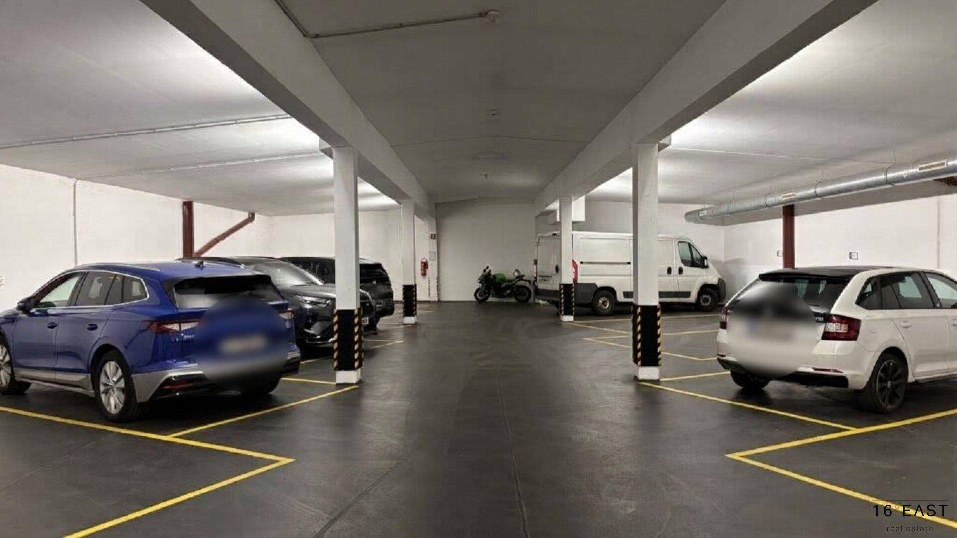 Geräumige Tiefgarage mit mehreren geparkten Fahrzeugen und klar markierten Stellplätzen.