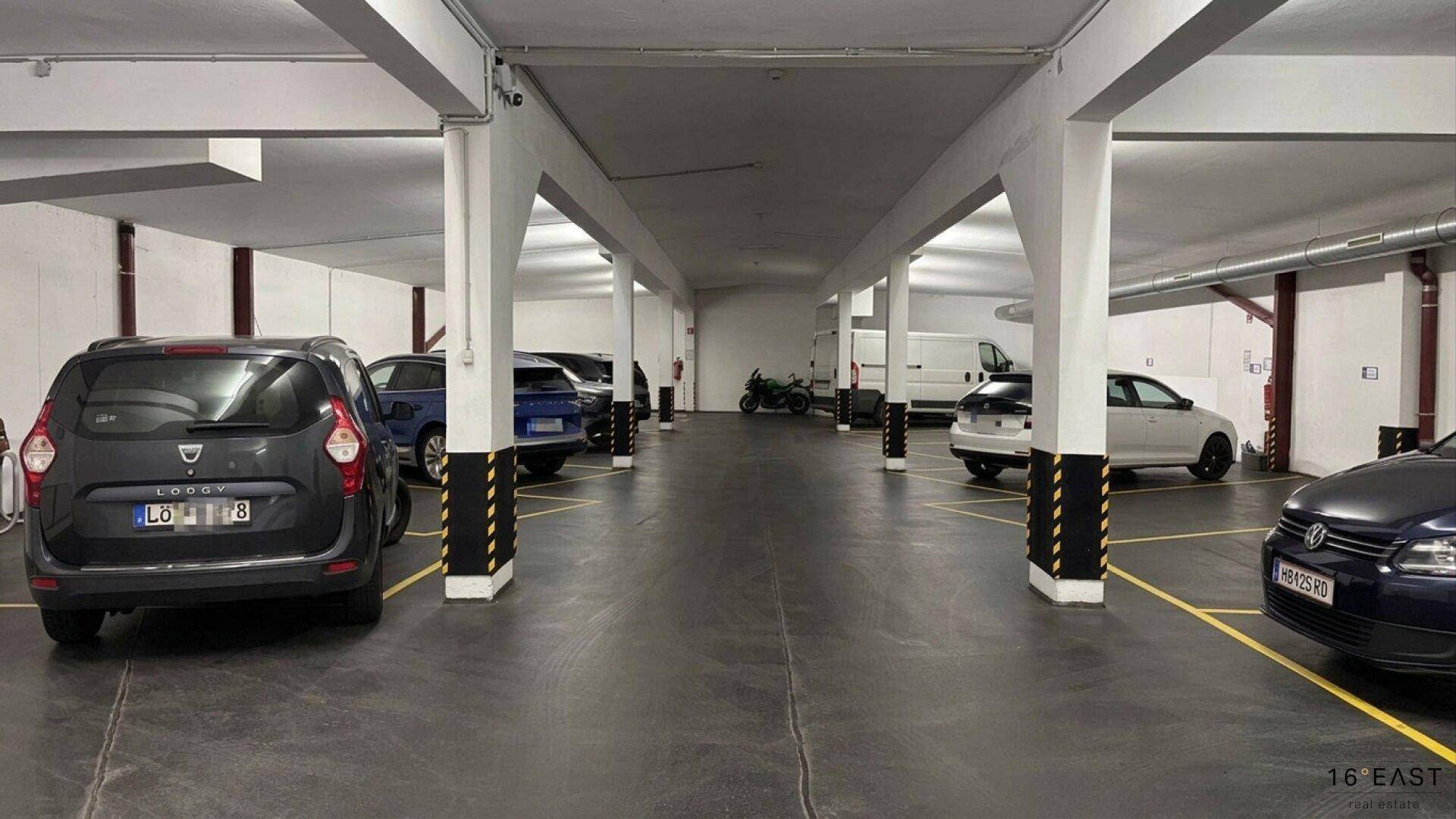 Tiefgarage mit Säulen und ausreichend Platz für Fahrzeuge, gut beleuchtet und organisiert.