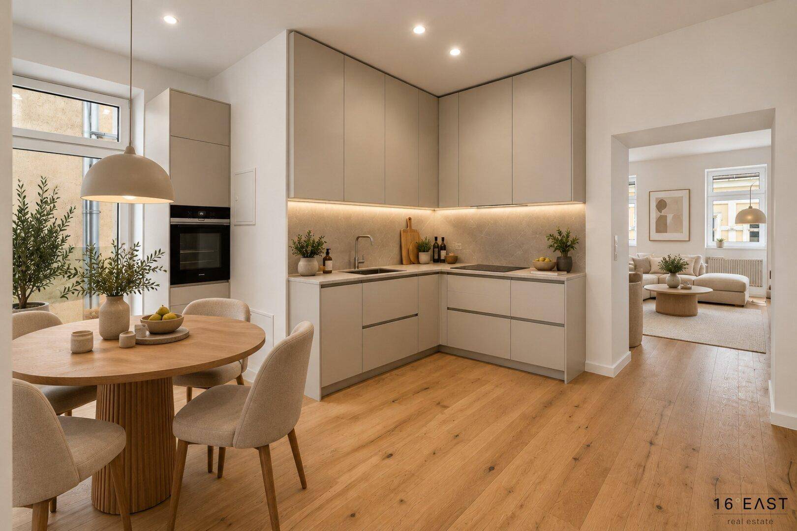 Moderne Einbauküche in hellen Farbtönen mit Essbereich, Holzboden und Blick ins Wohnzimmer.