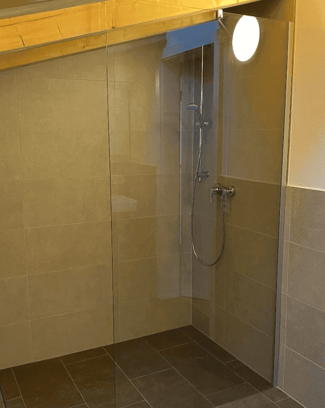 Modernes Badezimmer mit begehbarer Dusche und großformatigen Fliesen in neutralen Farbtönen.