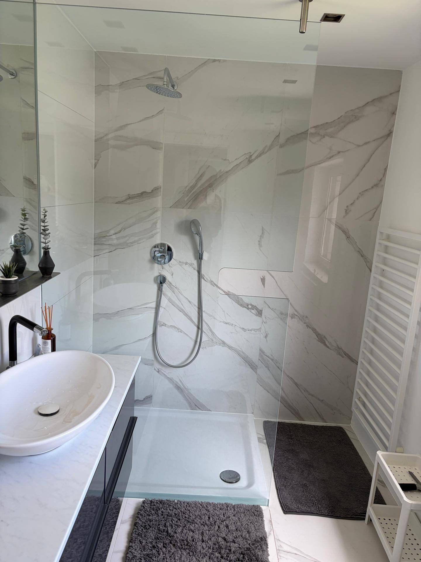 Modernes Badezimmer mit großer begehbarer Dusche, Marmoroptik-Fliesen und ovalem Waschbecken.