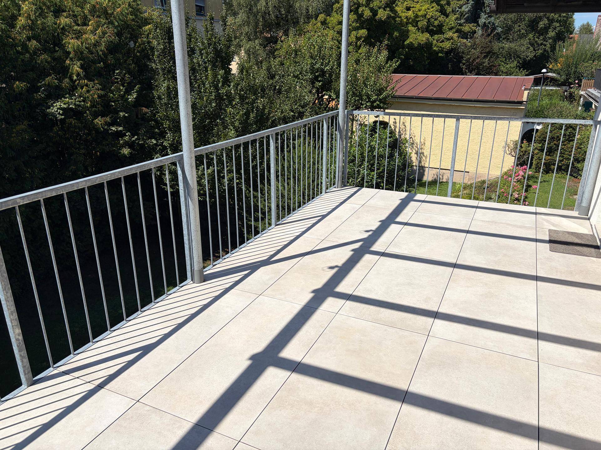 Heller Balkon mit Fliesenboden und weitem Blick auf die umliegende grüne Landschaft.