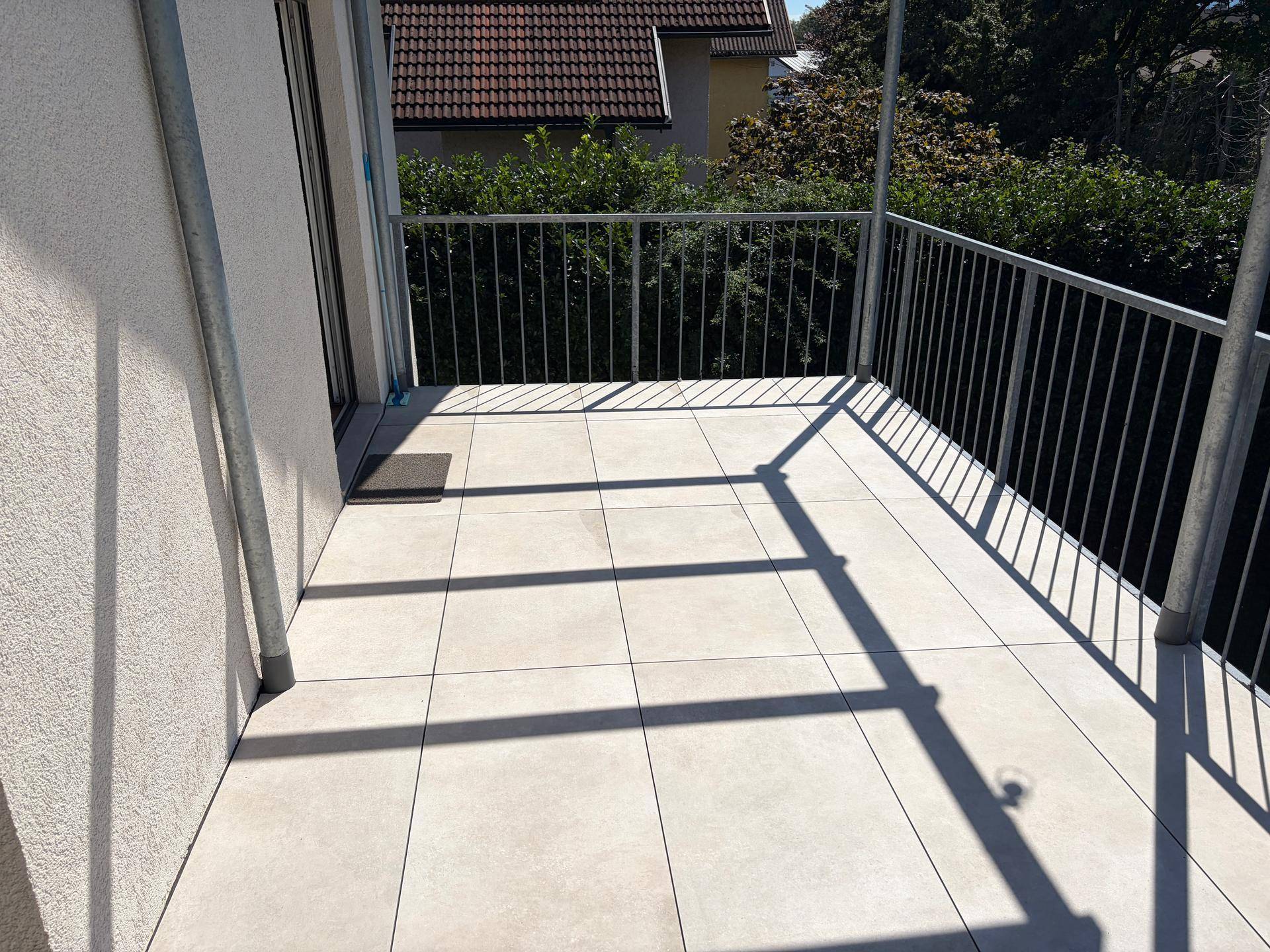 Geräumiger Balkon mit Fliesenboden und Metallgeländer, ideal zum Entspannen im Freien.