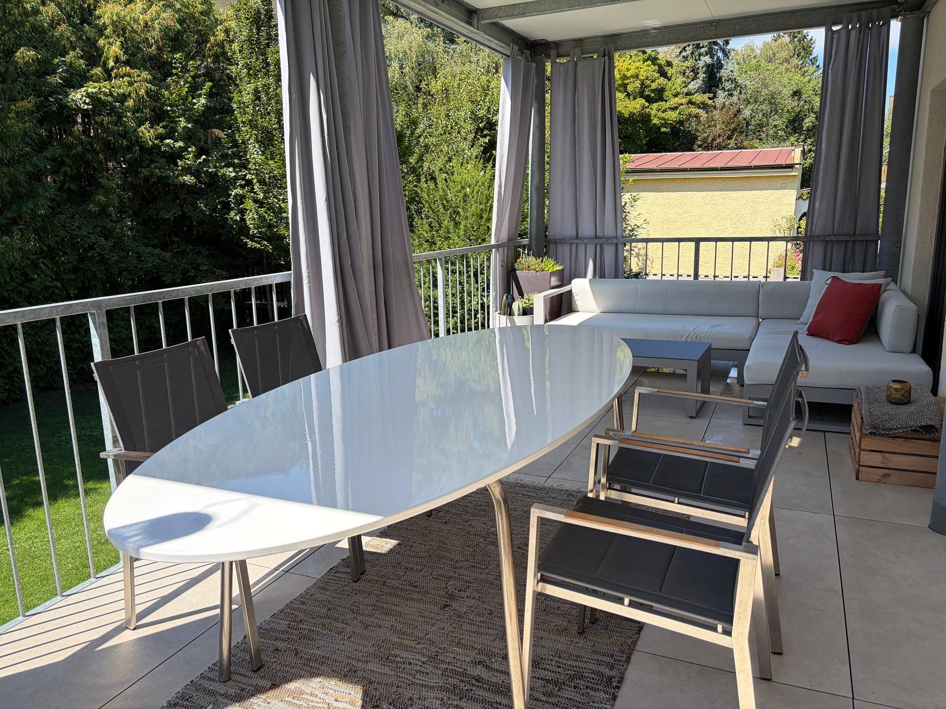 Große überdachte Terrasse mit Esstisch, Lounge-Möbeln und Blick ins Grüne.