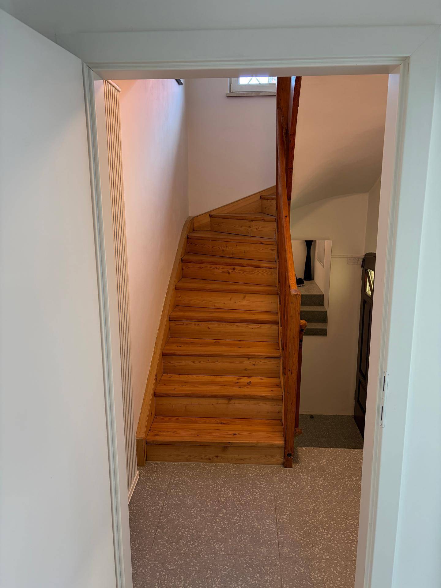 Holztreppe mit hellem Geländer, die die verschiedenen Etagen des Hauses verbindet.
