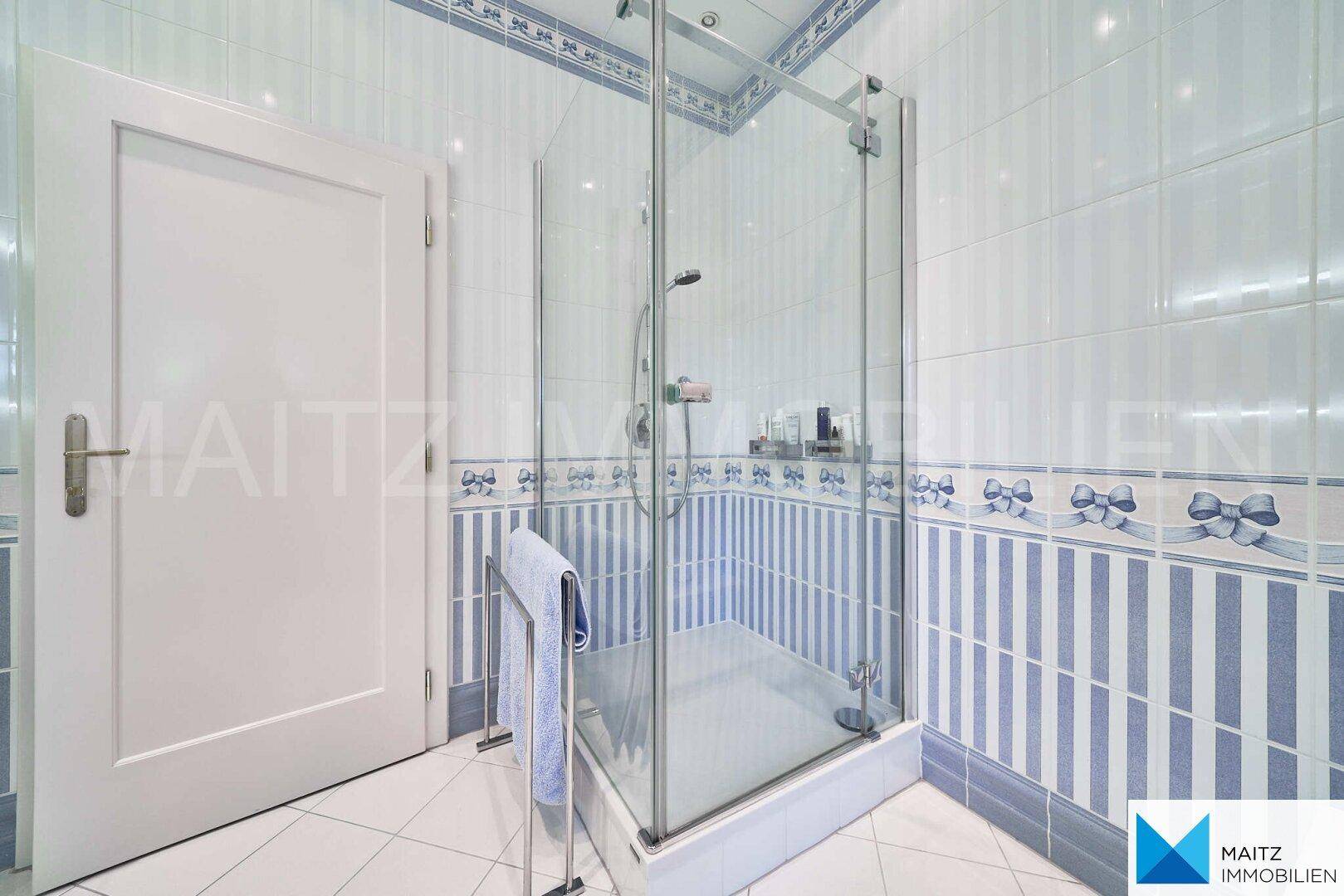 Duschkabine im Badezimmer mit Glaswänden und blauen und weißen Fliesen.