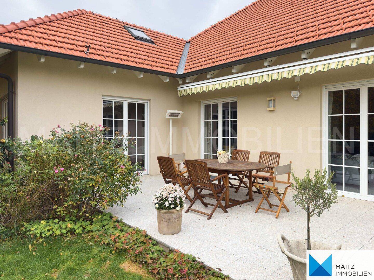 Sonnige Terrasse mit Gartenmöbeln und Blick auf den gepflegten Garten.