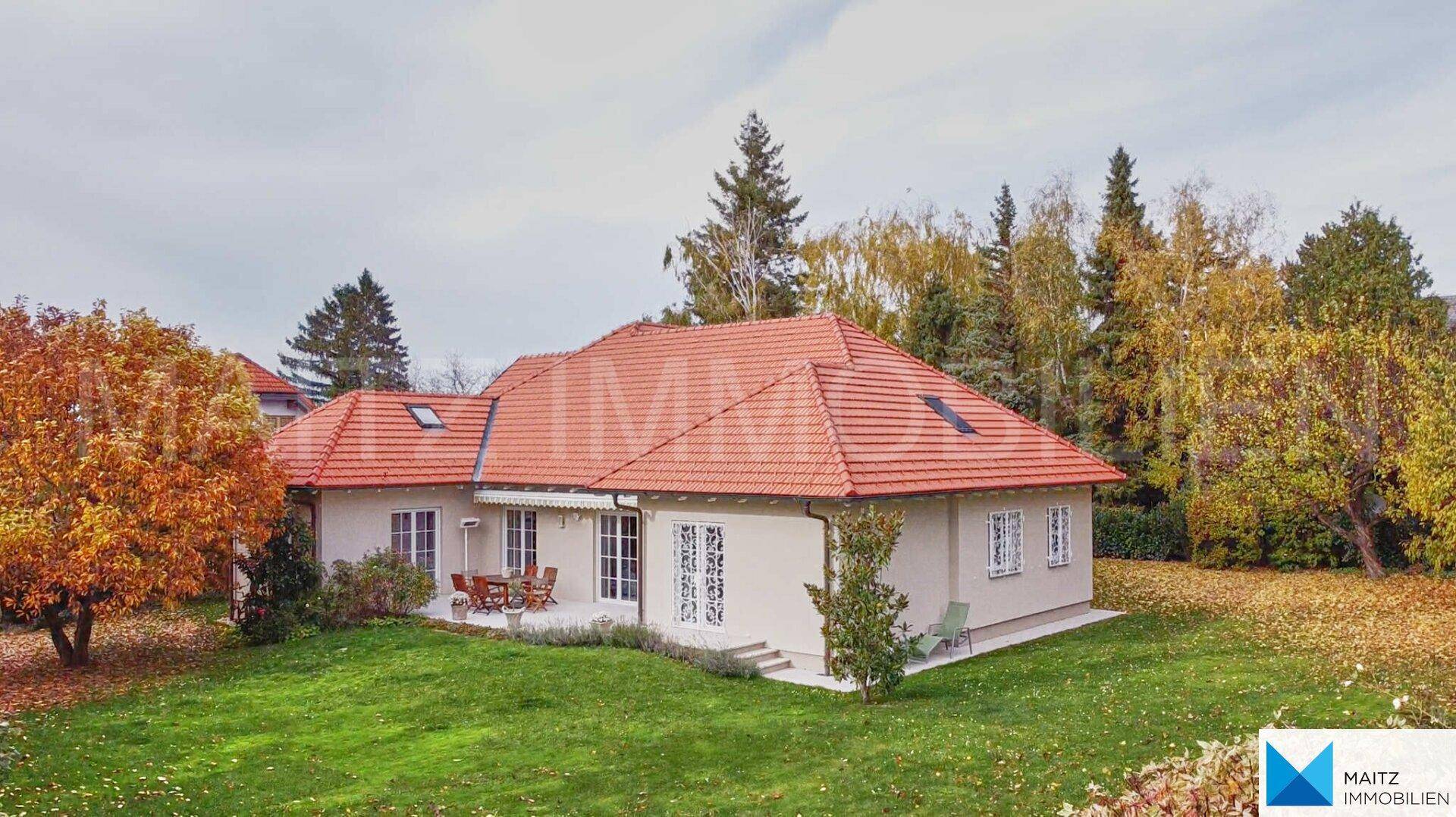 Das Haus mit großem Garten und Terrasse, umgeben von Bäumen im Herbst.