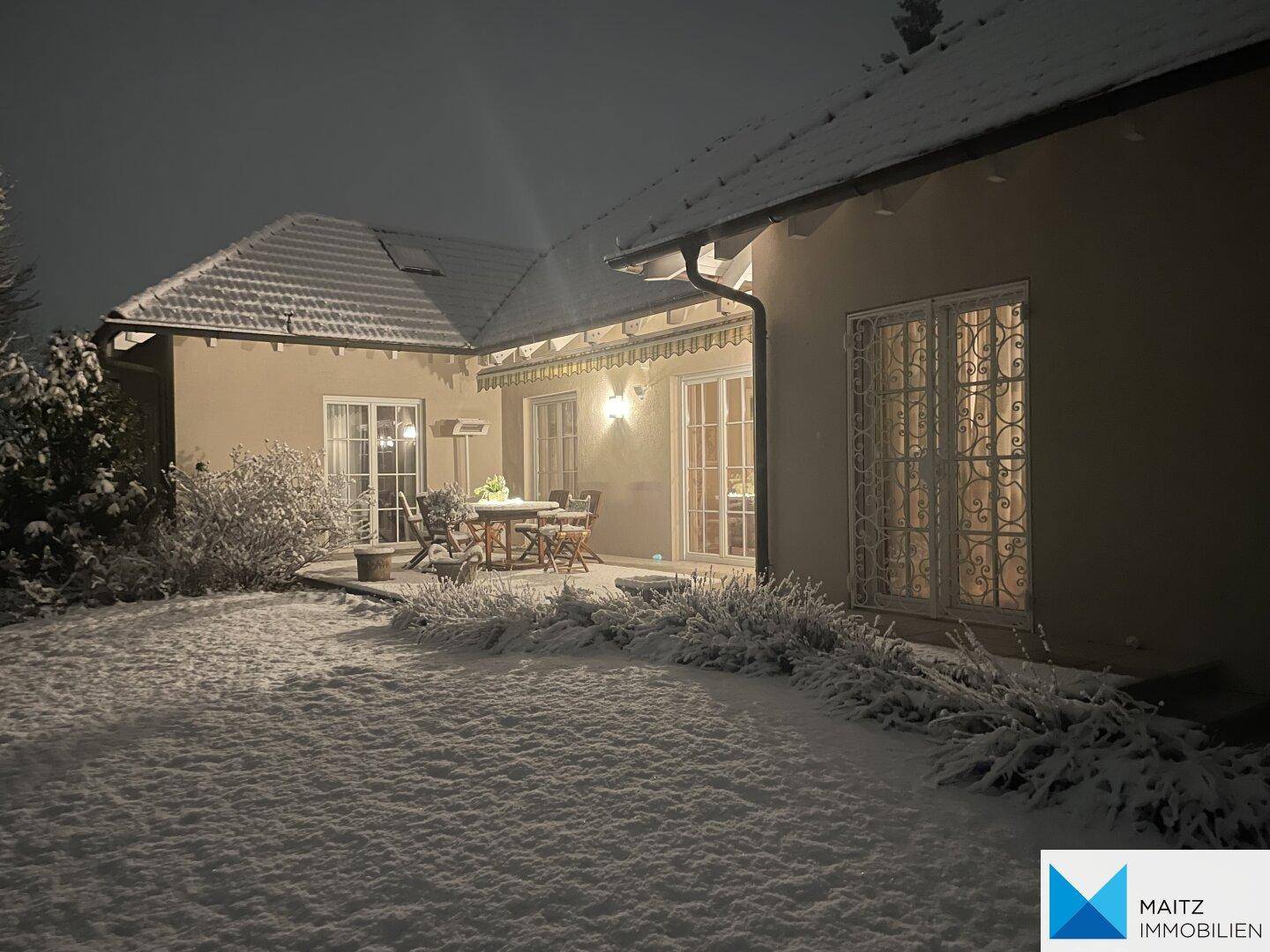Das Haus mit Terrasse und verschneitem Garten in der Winternacht.