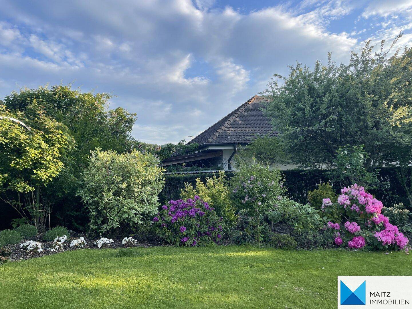 Gepflegter Garten mit blühenden Sträuchern und Blick auf das Haus.