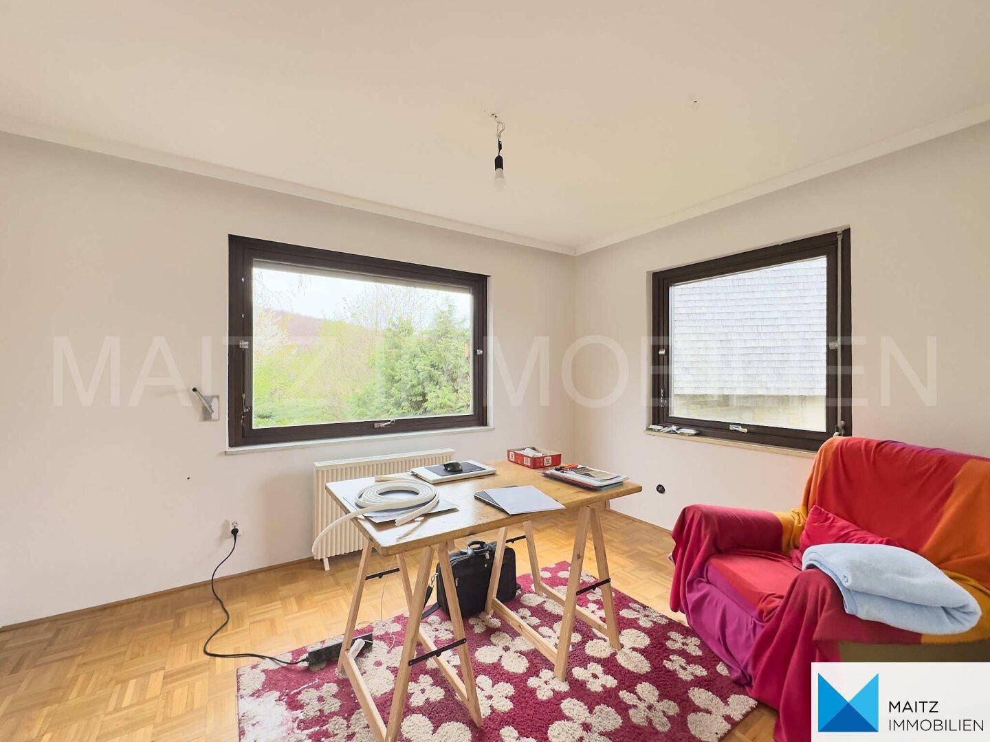 Schlafzimmer oder Arbeitszimmer mit zwei Fenstern und Blick ins Grüne.