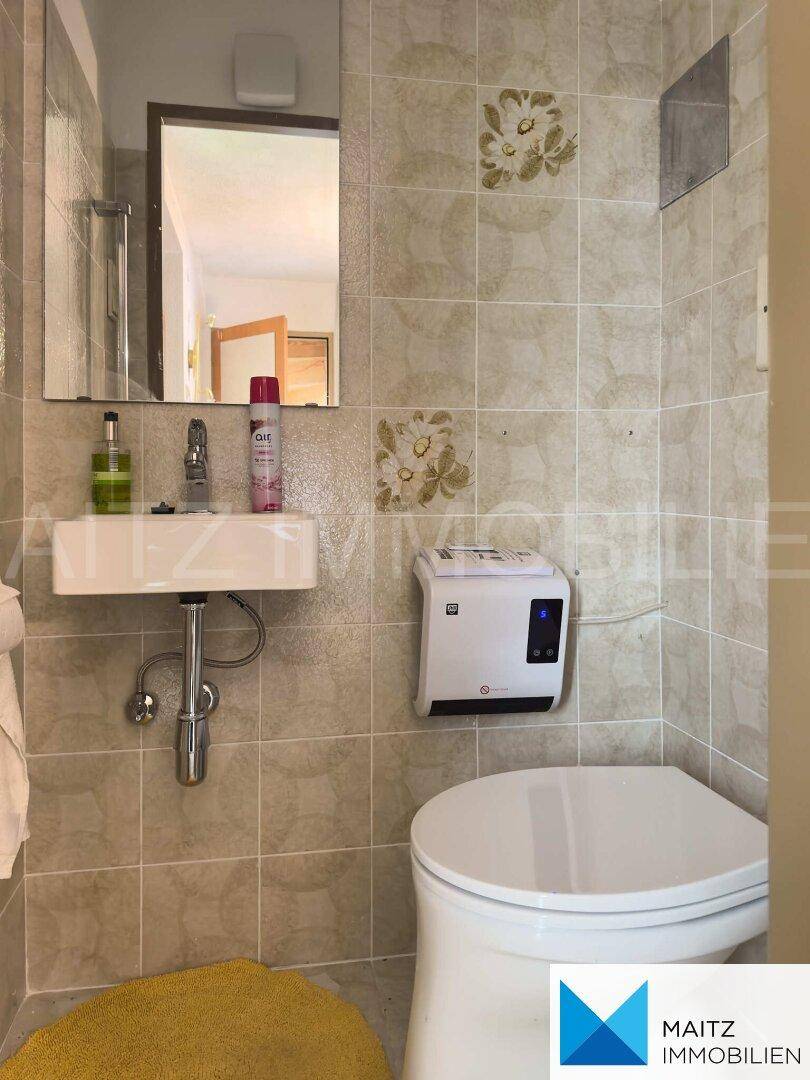 Kleines Gäste-WC mit Toilette, Handwaschbecken und hellen Fliesen.