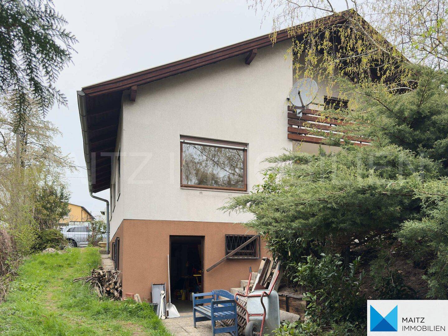 Seitenansicht des Hauses mit einem Eingang im Untergeschoss und einem Balkon im Obergeschoss.