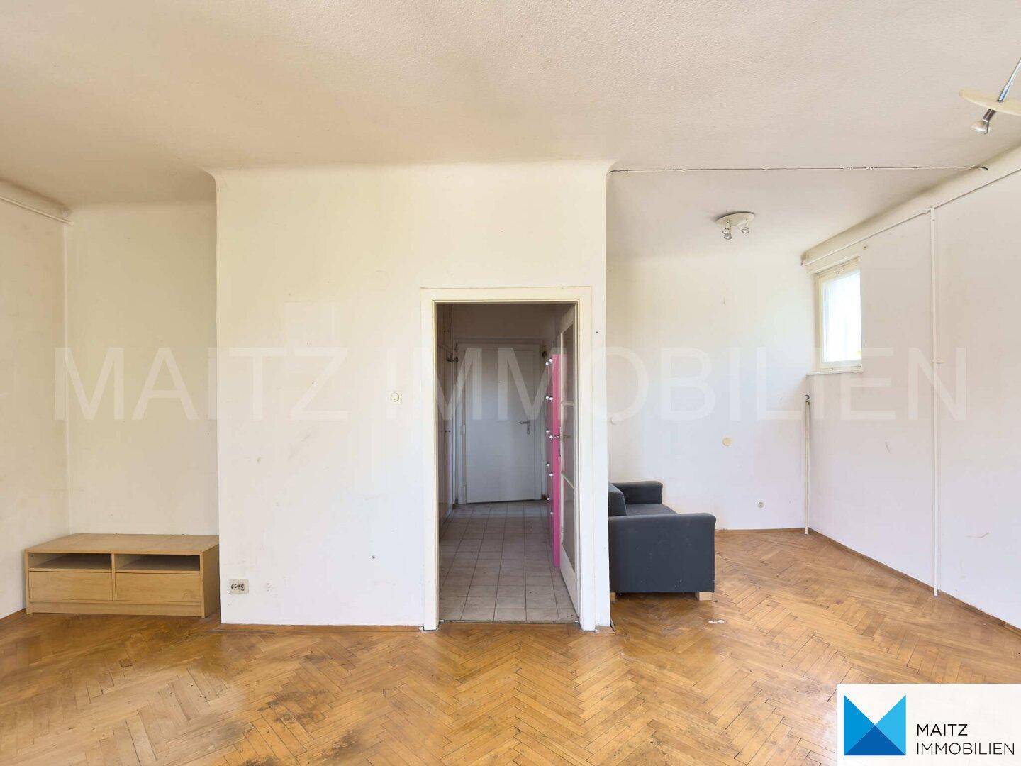 Wohnzimmer mit Holzboden, einem niedrigen Sideboard und einem Sofa, bereit zur individuellen Gestaltung.
