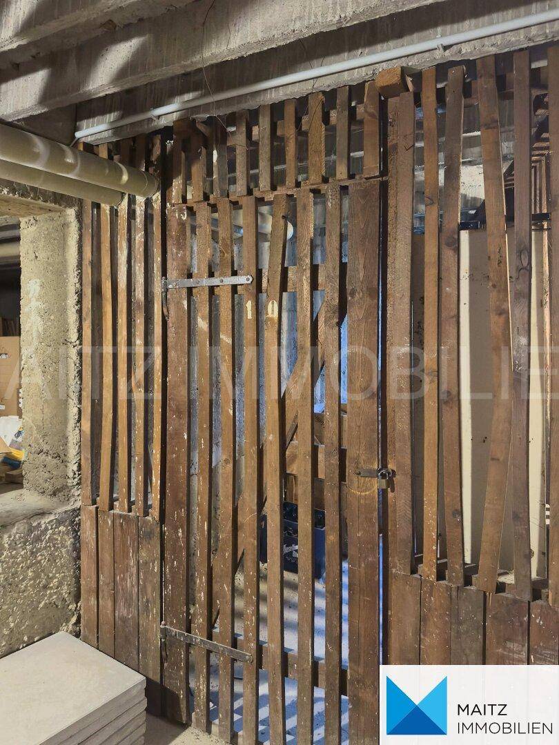 Kellerabteil mit Holzlattenwänden, bietet einfachen Stauraum in einem rustikalen Ambiente.