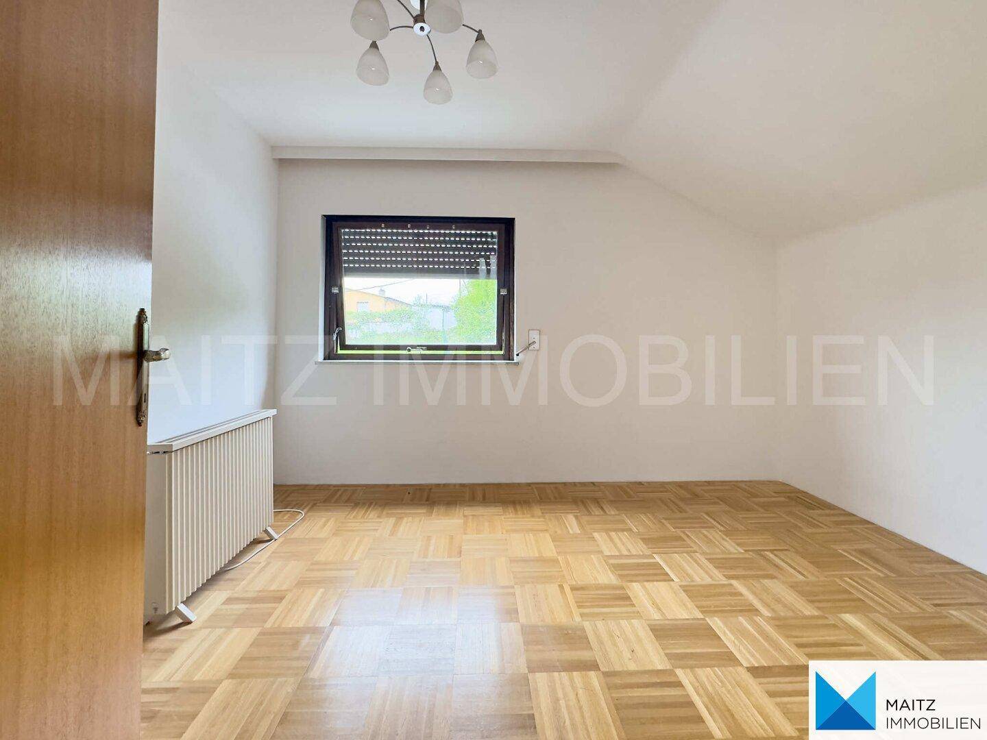 Helles Schlafzimmer mit Parkettboden, Fenster mit Rollladen und Heizkörper, bietet viel Gestaltungspotenzial.