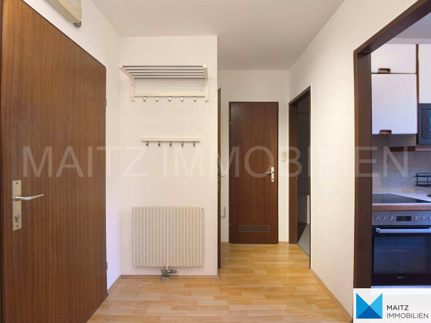 Heller Flur mit Parkettboden und Garderobe, angrenzend an die Küche und weitere Zimmer.