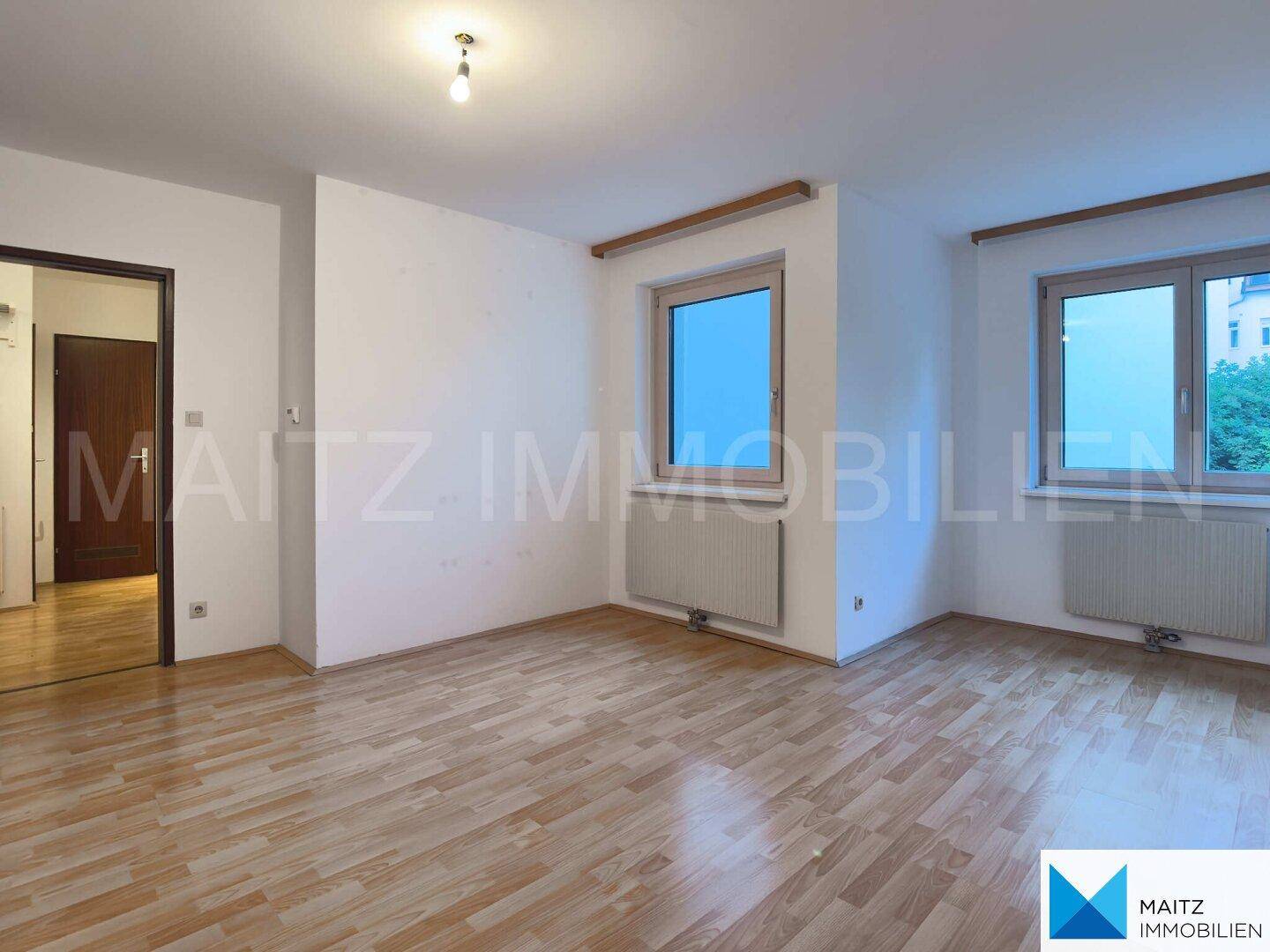 Geräumiges Zimmer mit hellem Parkettboden und zwei Fenstern, vielseitig nutzbar.