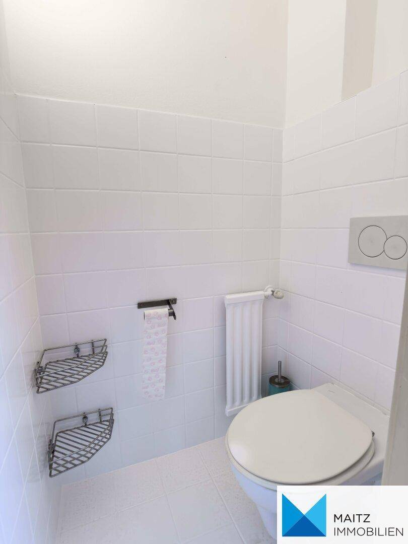 Separate Toilette mit weißen Fliesen und Wand-WC.