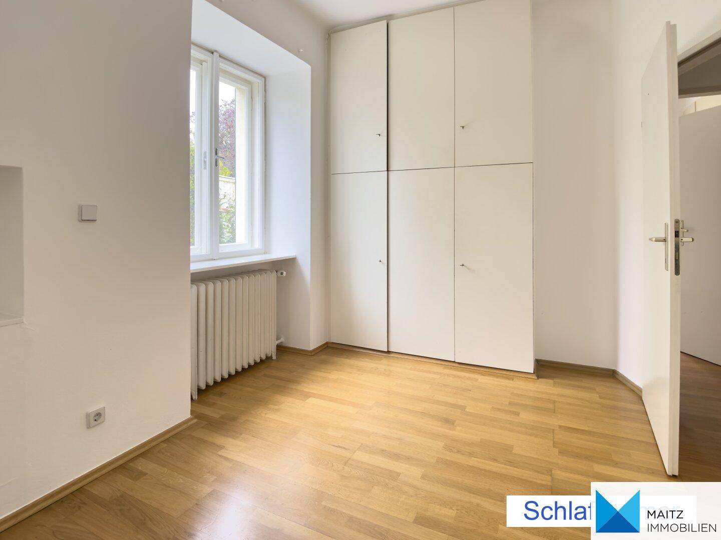 Helles Schlafzimmer mit Einbauschränken und einem Fenster, das den Raum erhellt.