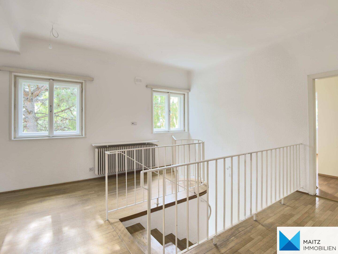Heller Flurbereich im Obergeschoss mit Parkettboden und Geländer zur Treppe.