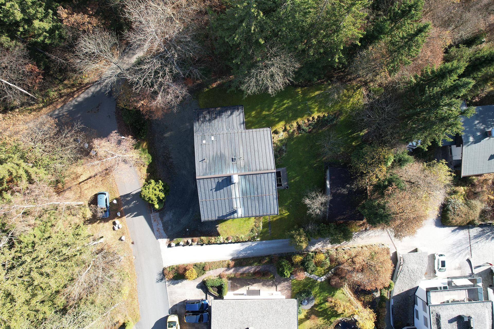 Vogelperspektive eines Hauses mit Solaranlage auf dem Dach, umgeben von Bäumen.