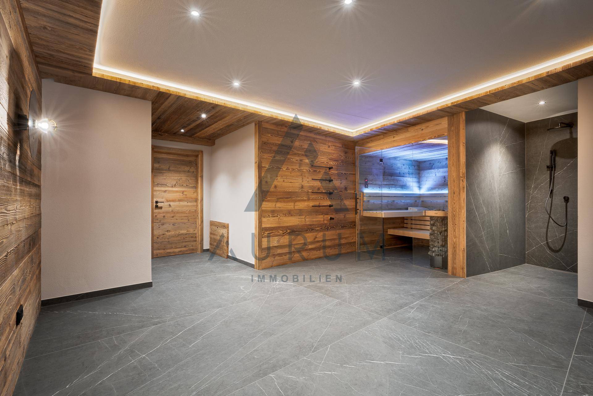 Geräumiger Wellnessbereich mit moderner Sauna, Dusche und stilvollen Fliesenböden.