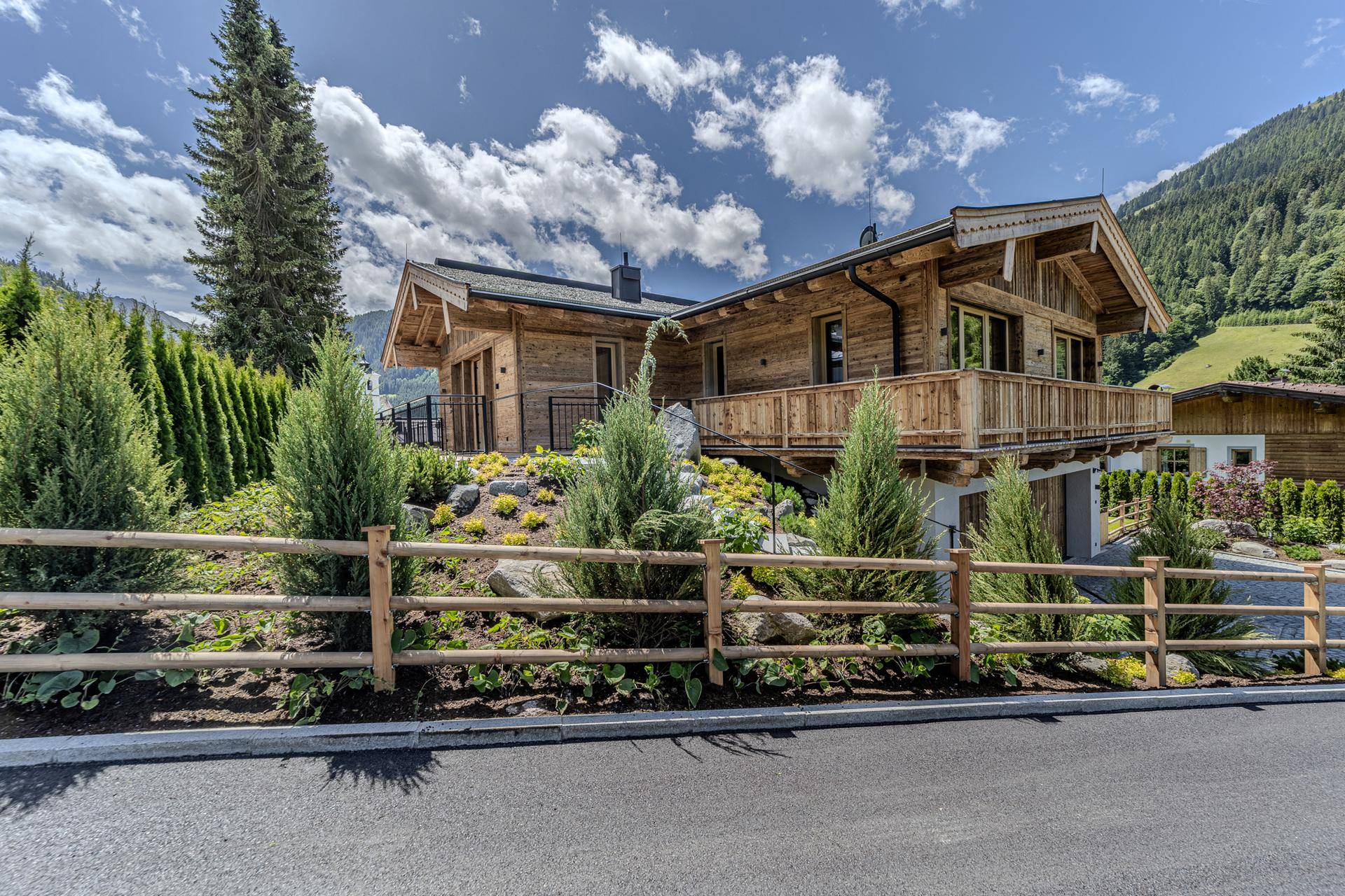 Chalet-Villa in alpiner Landschaft mit Holzzaun, gepflegter Bepflanzung und Bergblick.