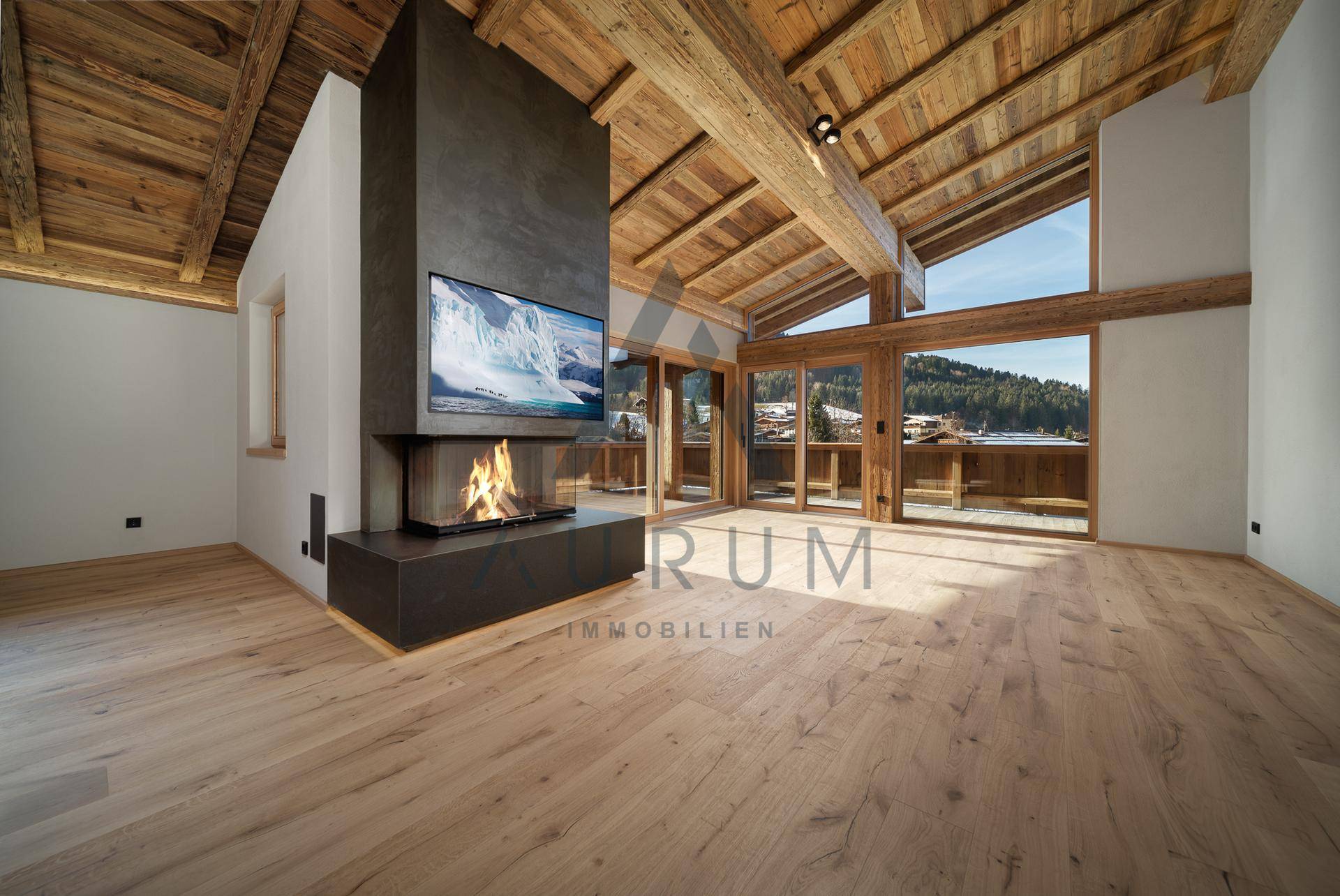 Helles Wohnzimmer mit hohen Holzdecken, modernem Kamin und Zugang zu einem Balkon mit Bergblick.