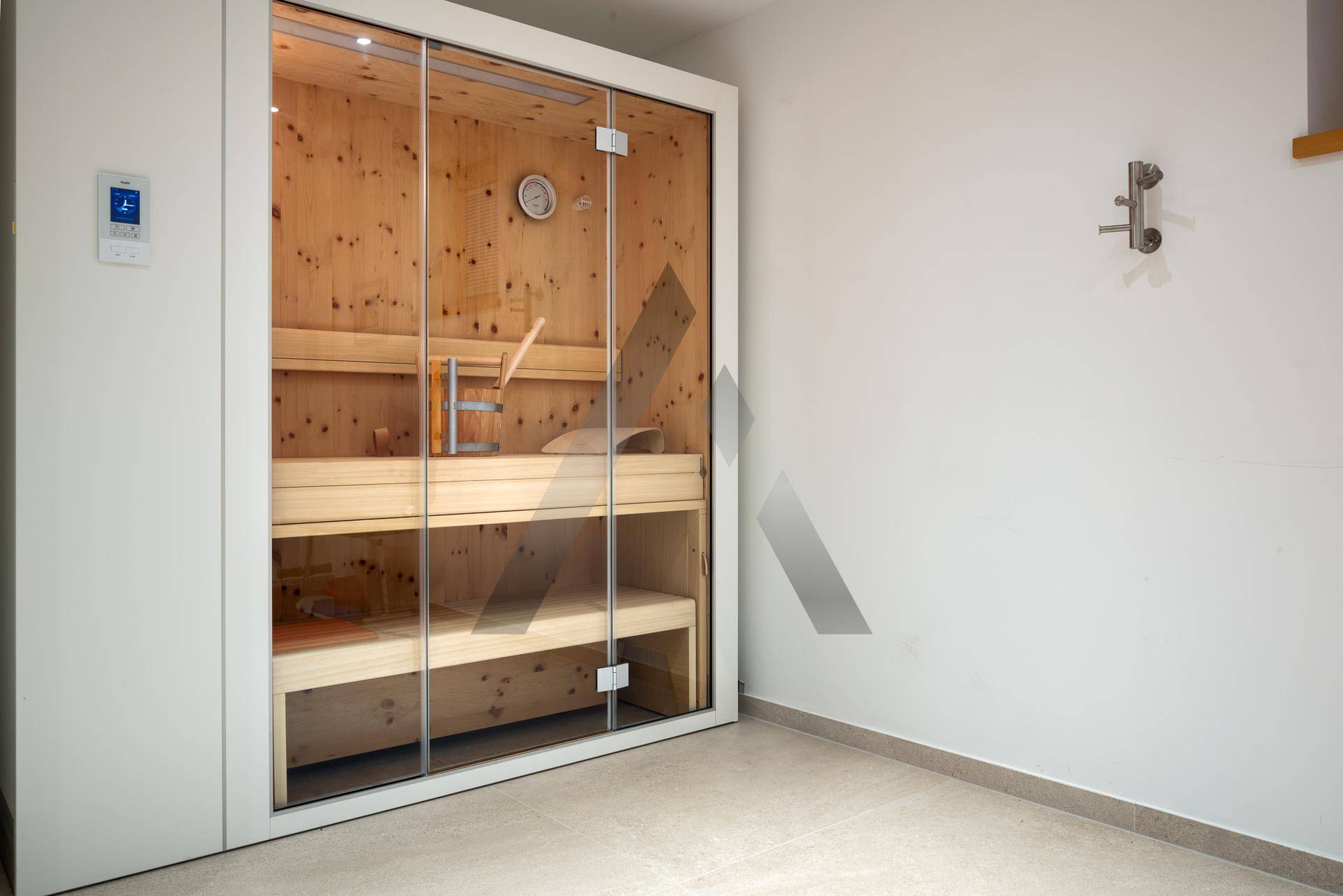 Moderne Sauna mit Holzbänken und Glastür, ideal zur Entspannung und Erholung.